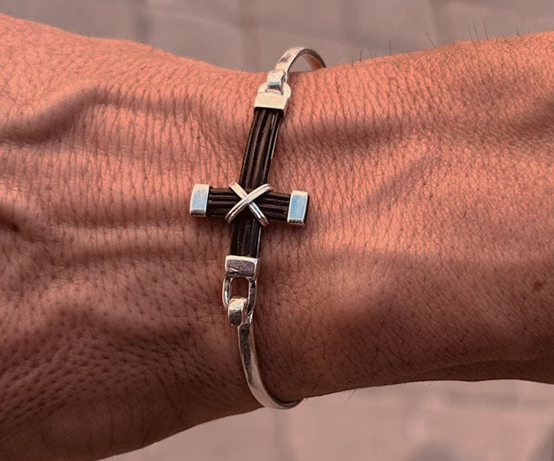 Pulsera de cruz de plata con pelo de búfalo colocada en la muñeca de un hombre diseño elegante