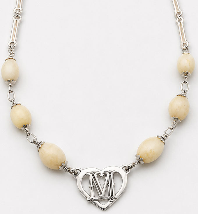 detalle del collar perla venado con corazon en plata con letra M en el centro
