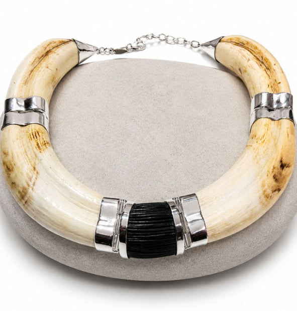 Collar completo de colmillos de facochero rematados con virolas de plata de ley y adorno de pelo de búfalo negro en el centro.