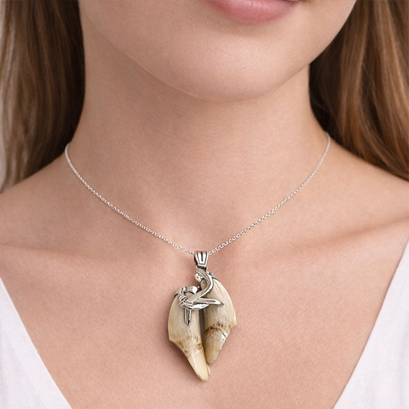 Detalle del colgante de 5 cm con dos colmillos de jabalí entrelazados en plata 925 | Joyas de Caza en el cuello de la modelo
