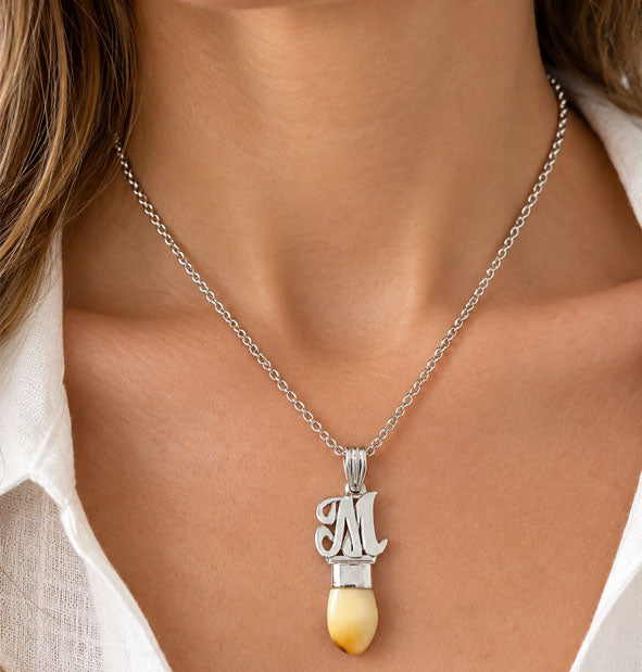 collar perla venado letra M en plata detalle del cuello de la modelo