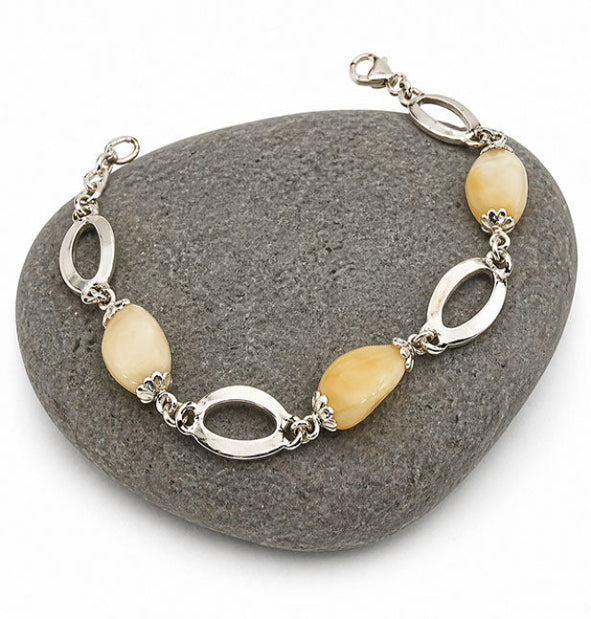 Detalle perlas de venado naturales talladas en forma oval con engaste floral en pulsera de plata 925