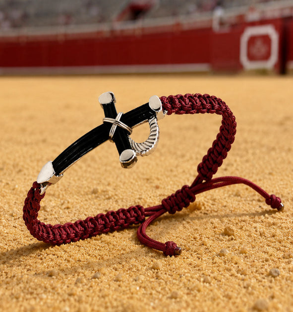 <pulsera estoque taurino con pelo de bufalo y plata de ley atado con trenza algodon  apoyado en la arena del rueda de la plaza de las ventas