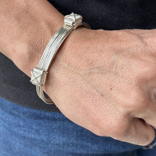 pulsera nudos corredizos 9 hilos de plata apoyado en la mano