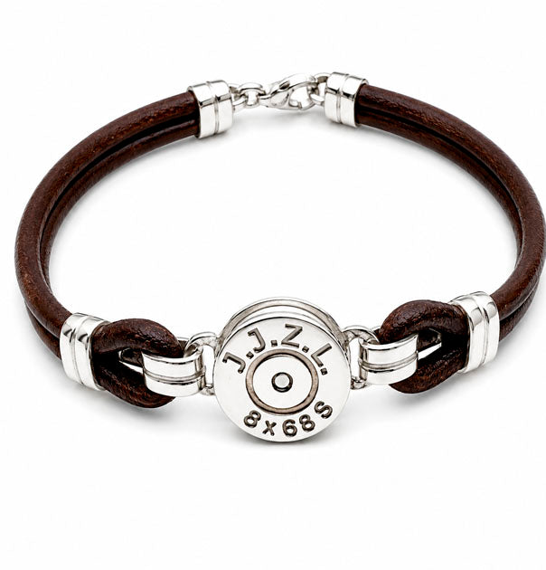 Detalle de réplica de culata de bala grabada con iniciales y calibre en pulsera de cuero y plata